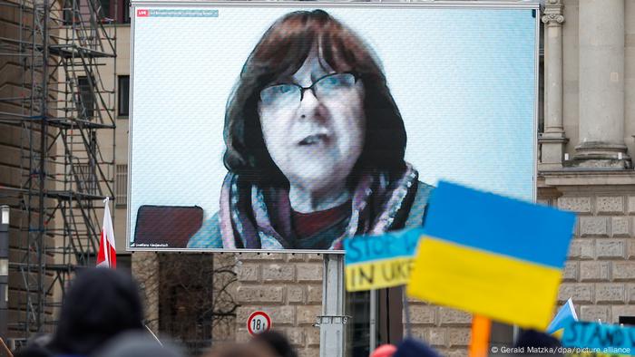 A woman on a screen with a Ukraine flag in the foreground