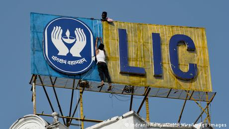 A worker fixes light chain on LIC Life Insurance Corporation logo in Kolkata, India