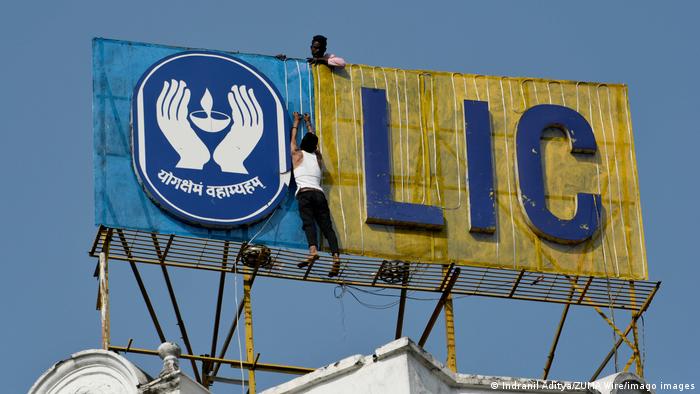 A worker fixes light chain on LIC Life Insurance Corporation logo in Kolkata, India