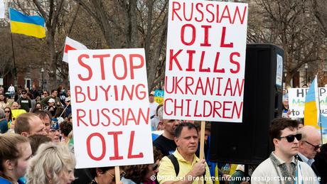 People with signs saying ''Stop buying Russian oil'' and ''Russian oil kills Ukrainian children'' at a rally in support of Ukraine held in front of the White House
