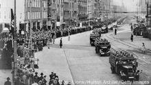circa 1940: Nazi troops and armoured divisions driving along a main street in Amsterdam, on a route from Central Station past the Queen's Palace. (Photo by Three Lions/Hulton Archive/Getty Images)