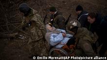 Ukrainian soldiers and militiamen carry a woman in a wheelchair as the artillery echoes nearby, while people flee Irpin on the outskirts of Kyiv, Ukraine, Monday, March 7, 2022. (AP Photo/Emilio Morenatti)