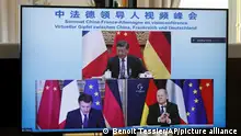 A television screen shows French President Emmanuel Macron, German Chancellor Olaf Scholz, below right, and Chinese President Xi Jinping, top, discussing the Ukraine crisis during a video-conference at the Elysee Palace in Paris, Tuesday, March 8, 2022. Safe corridors intended to let civilians escape the Russian onslaught in Ukraine could open Tuesday, officials from both sides said, though previous efforts to establish evacuation routes crumbled amid renewed attacks. (Benoit Tessier/Pool via AP)