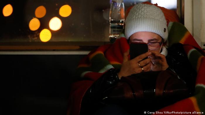 Ukrainian refugee uses her phone at a bus station in Poland