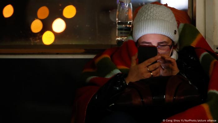 Ukrainian refugee uses her phone at a bus station in Poland