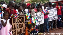 Holding placards with pro russian slogans, demonstrators gather in Bangui on March 5, 2022 during a rally in support of Russia. - A hundred people participated Saturday in Bangui, the capital of the Central African Republic, in a demonstration in support of Russia in its offensive against Ukraine. The demonstrators gathered at the foot of a statue, inaugurated at the end of 2021 by President Faustin Archange Touadéra, representing Russian fighters who protect a woman and her children. Many of them waved Russian and Central African flags in the heart of the capital, near the university. (Photo by Carol VALADE / AFP) (Photo by CAROL VALADE/AFP via Getty Images)