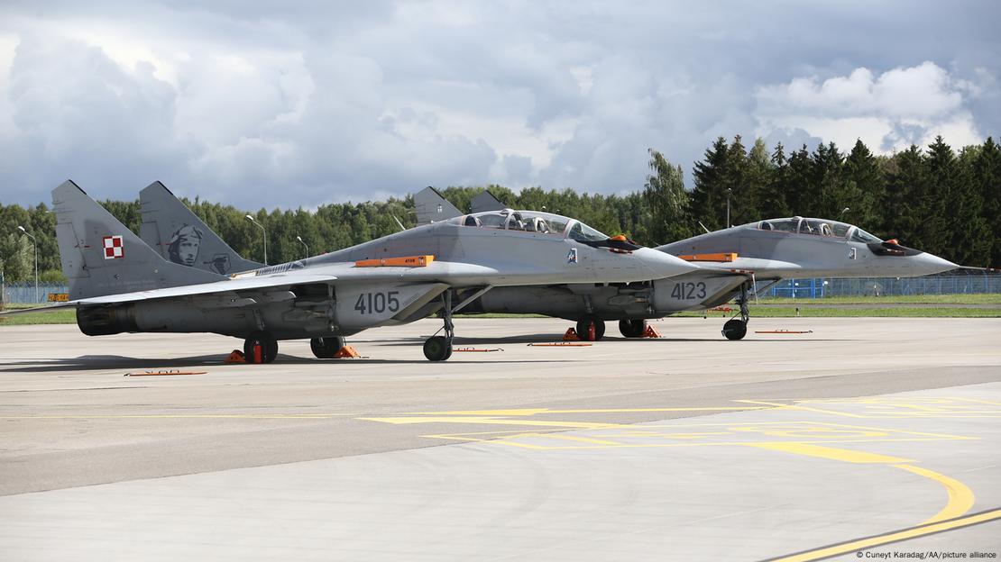 A imagem mostra dois caças MiG-29 que pertencem à Polônia na pista de uma base aérea.