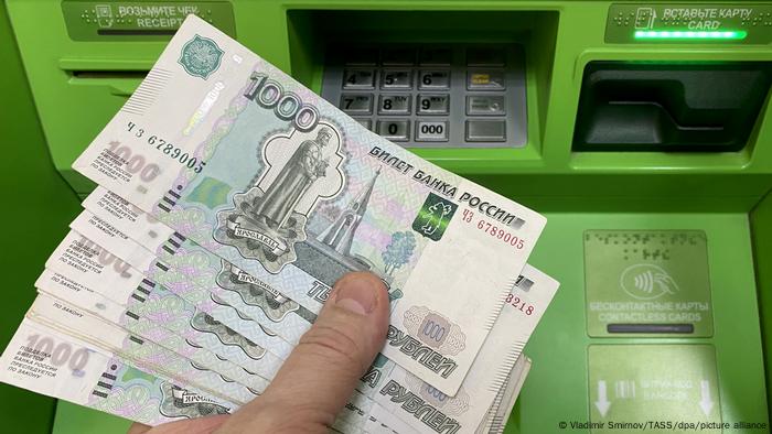  A person holds cash withdrawn from an ATM machine at a Sberbank branch
