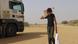 A child carries aid distributed by charity organizations on a dirt road