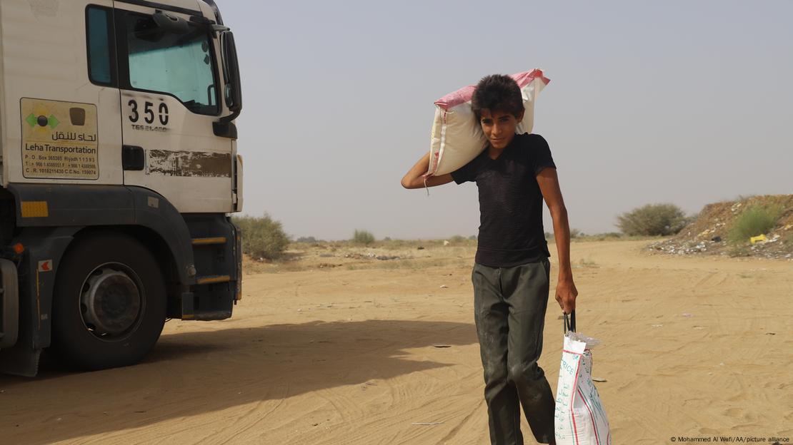 A child carries aid distributed by charity organizations on a dirt road