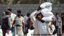 Yemeni workers carry bags of aid.