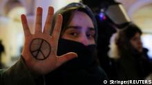 A demonstrator shows a peace symbol painted on her hand, next to a law enforcement officer, during an anti-war protest against Russia's invasion of Ukraine, in Saint Petersburg, Russia March 2, 2022. REUTERS/Stringer