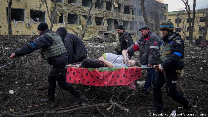 Українські рятувальники несуть поранену вагітну жінку з пошкодженого внаслідок обстрілу пологового будинку в Маріуполі 