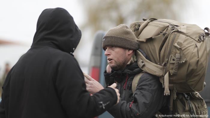 A man with a large backpack talking to another man