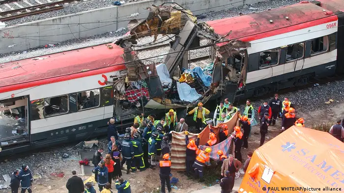 Policiais e equipes de resgate em frente a um vagão de trem explodido