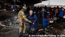 07.03.22 *** TOPSHOT - A Ukrainian serviceman helps evacuees gathered under a destroyed bridge, as they flee the city of Irpin, northwest of Kyiv, on March 7, 2022. - Ukraine dismissed Moscow's offer to set up humanitarian corridors from several bombarded cities on March 7, 2022, after it emerged some routes would lead refugees into Russia or Belarus. The Russian proposal of safe passage from Kharkiv, Kyiv, Mariupol and Sumy had come after terrified Ukrainian civilians came under fire in previous ceasefire attempts. (Photo by Dimitar DILKOFF / AFP) (Photo by DIMITAR DILKOFF/AFP via Getty Images)