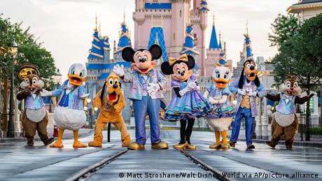 Disney characters pose in front of disney world entrance 
