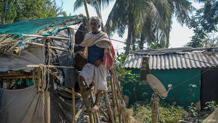 A man standing an a ladder to a makeshift hut 
