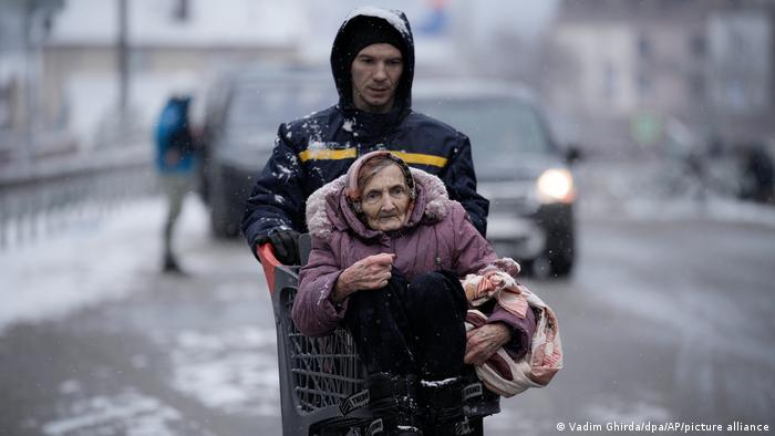 A man pushes an elderly woman in a shopping cart