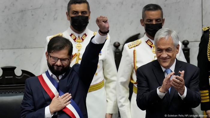 Con banda, como manda la tradición, pero sin corbata, y con el puño izquierdo en alto, junto a Sebastián Piñera, su antecesor en el cargo: Gabriel Boric toma posesión como presidente de Chile. 