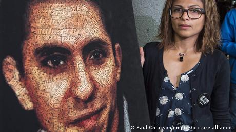 Raif Badawi's wife hold up a large photo of Badawi