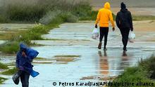 Migranten gehen in der Nähe des Aufnahmelagers Pournara außerhalb der Hauptstadt Nikosia durch den Regen. Der zypriotische Beauftragte für Kinderrechte sagte, dass unbegleitete Minderjährige im überfüllten Aufnahmelager für Migranten am Rande der Hauptstadt Nikosia weiterhin gegen die ihrer Meinung nach «miserablen» und «unhygienischen» Bedingungen dort protestierten. +++ dpa-Bildfunk +++