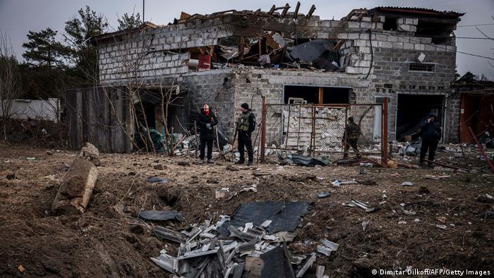 Foto de unas personas frente a una casa destruida por los bombardeos en Kiev.
