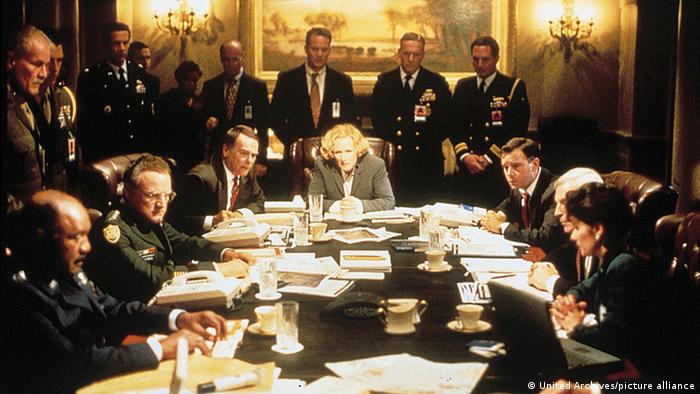 Film still Glenn Close in the film Air Force One, many military men around a table, one woman