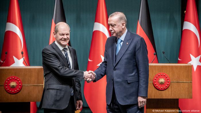 Ein lächelnder Olaf Scholz und ein ernst dreinblickender Recep Tayyip Erdogan schütteln sich die Hände