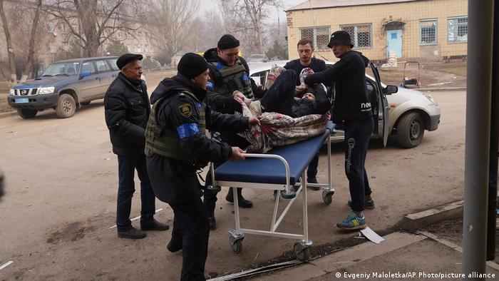 Ukrainian servicemen and volunteers carry a man injured during a shelling attack into hospital number 3 in Mariupol, Ukraine