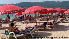 11.03.22 *** Tourists lounge under umbrellas along Patong Beach in Phuket, Thailand, Friday, March 11, 2022. Thousands of Russian tourists are stranded in Thailand's beach resorts because of the war in Ukraine, many unable to pay their bills or return home because of sanctions and canceled flights. The crisis in Europe also put a crimp in recovery plans for the Southeast Asian nation’s tourism industry, which has hosted more visitors from Russia than any of its neighbors before the pandemic hit. (AP Photo/Salinee Prab)