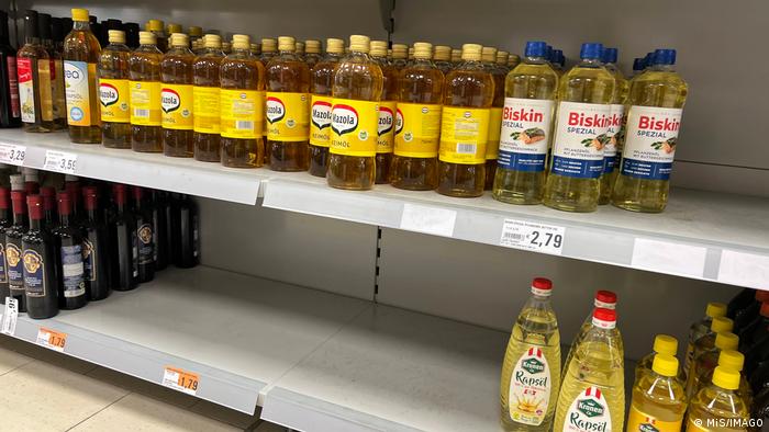 Supermarket shelves with food oil bottles, low-priced section is empty