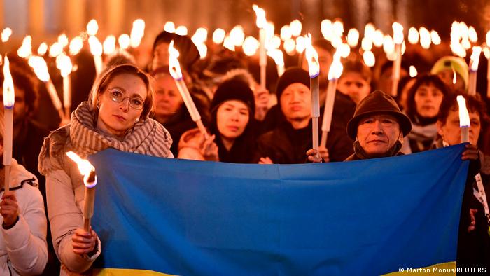 Crowd of people holding lit candles and Ukrainian flag