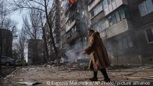 A woman walks past a burning apartment building after shelling in Mariupol, Ukraine, Sunday, March 13, 2022. (AP Photo/Evgeniy Maloletka)