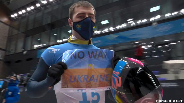 Bei den Olympischen Winterspielen hält Vladyslav Heraskevych ein Schild mit der Aufschrift No war in Ukraine hoch 