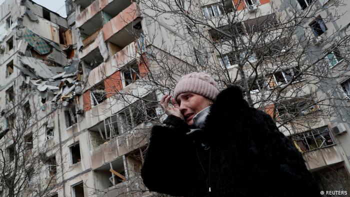 A crying woman with destroyed buildings in the background in Mariupol