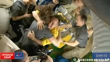 In this frame grab from video provided by Roscosmos, the crew of the International Space Station welcomes three Russian cosmonauts, dressed in yellow, after the new arrivals docked, Friday, March 18, 2022. The cosmonauts emerged from the Soyuz capsule wearing yellow flight suits with blue stripes, the colors of the Ukrainian flag. (Roscosmos via AP)
