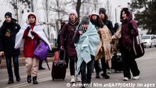 Ukrainian evacuees walk at the Ukrainian-Romanian border in Siret, northern Romania, on March 16, 2022. - More than three million people have fled Ukraine since the start of the invasion, the UN migration agency IOM says. Around half are minors, says the UN children's agency. (Photo by Armend NIMANI / AFP) (Photo by ARMEND NIMANI/AFP via Getty Images)