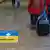 Два человека на главном вокзале Кельна катят чемоданы в направлении пункта приема беженцев из Украины