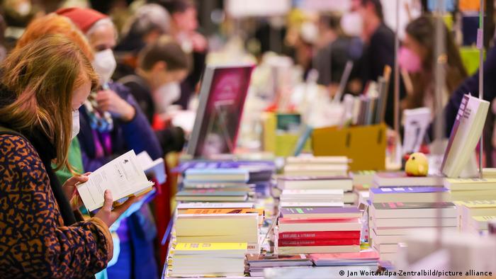 Besucherinnen und Besucher der Buchmesse Pop Up in Leipzig stöbern in Büchern