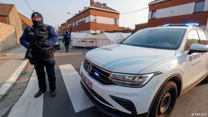 شرطي بلجيكي يقف بجانب سيارة شرطة 
