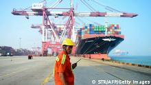 A Chinese worker looks on as a cargo ship is loaded at a port in Qingdao, eastern China's Shandong province on July 13, 2017. China's exports rose a forecast-beating 11.3 percent on-year in June, data showed July 13, fuelling hopes of stability in the world's second-largest economy. / AFP PHOTO / STR / China OUT (Photo credit should read STR/AFP via Getty Images)