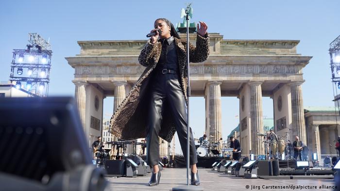 a singer performing in front of the Gate of Brandenburg.