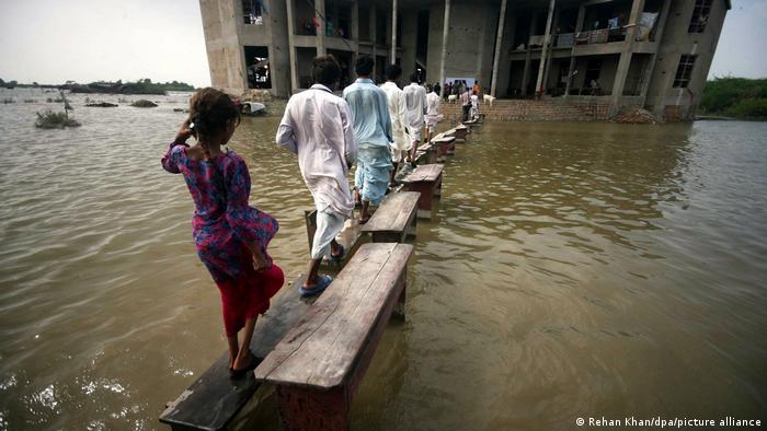 Bewohner bewegen sich im überschwemmten Khoski in Pakistan auf hohen Holzstegen 