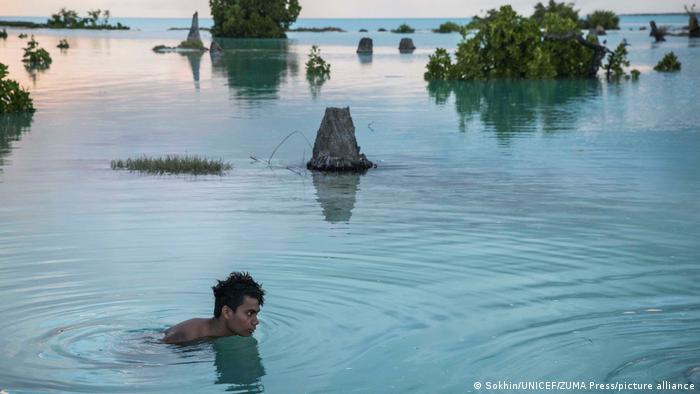 Peia Kararaua, 16, has to swim through a flooded area to reach his home in Aberao village