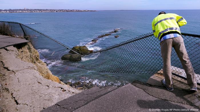 Public Services Director Bill Riccio peers down at debris along the historic Cliff Walk in Rhode Island