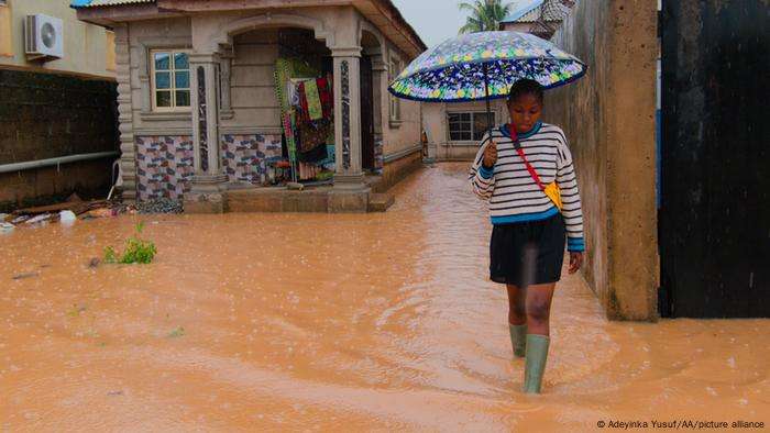 A Nigerian woman walks at a flooded place after heavy rains hit Lagos, Nigeria