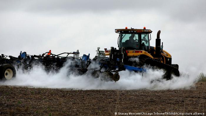 A tractor sprays fertilizer in a field of winter crops