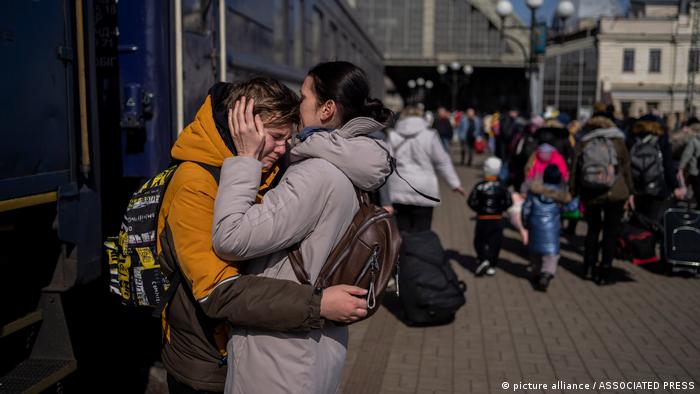 Seorang ibu memeluk putranya yang melarikan diri dari kota Mariupol dan tiba di stasiun kereta api di Lviv, Minggu (20/03)