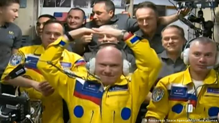 En esta foto tomada de un vídeo difundido por la Agencia Espacial Roscosmos, los austronautas rusos recién llegados a la EEI, con trajes amarillos.